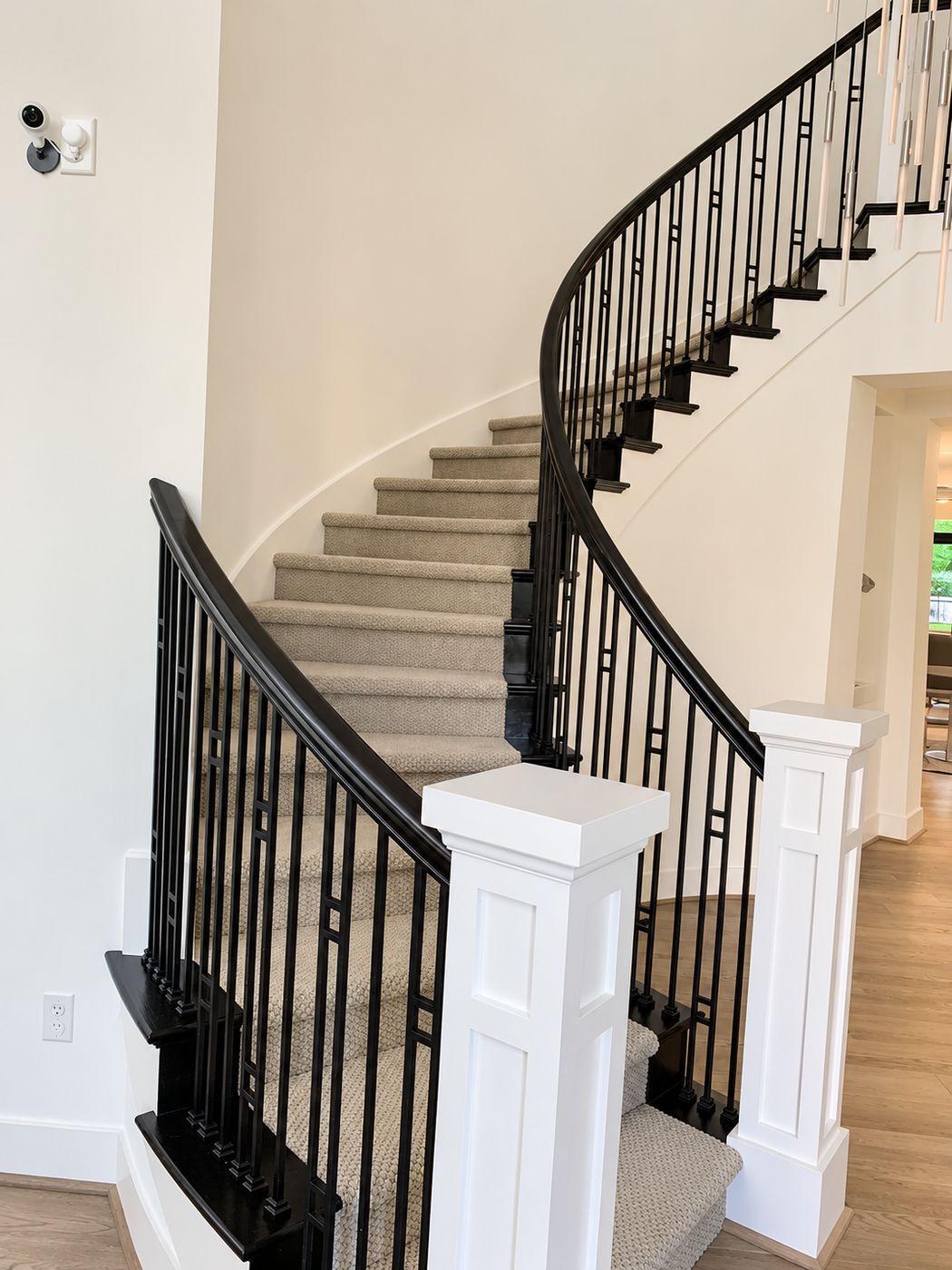 Curved staircase with a black handrail and white box newel posts