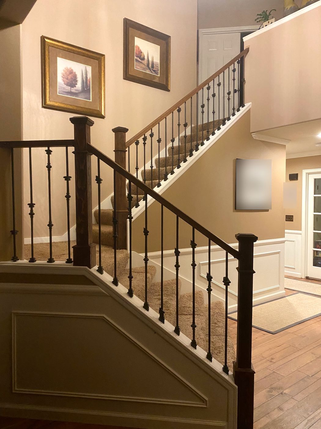 Staircase with iron balusters, stained handrail and carpeted treads
