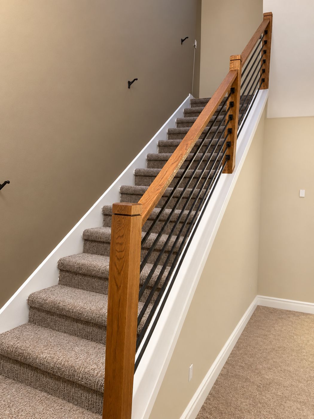 Carpeted staircase with an oak handrail and horizontal metal bars
